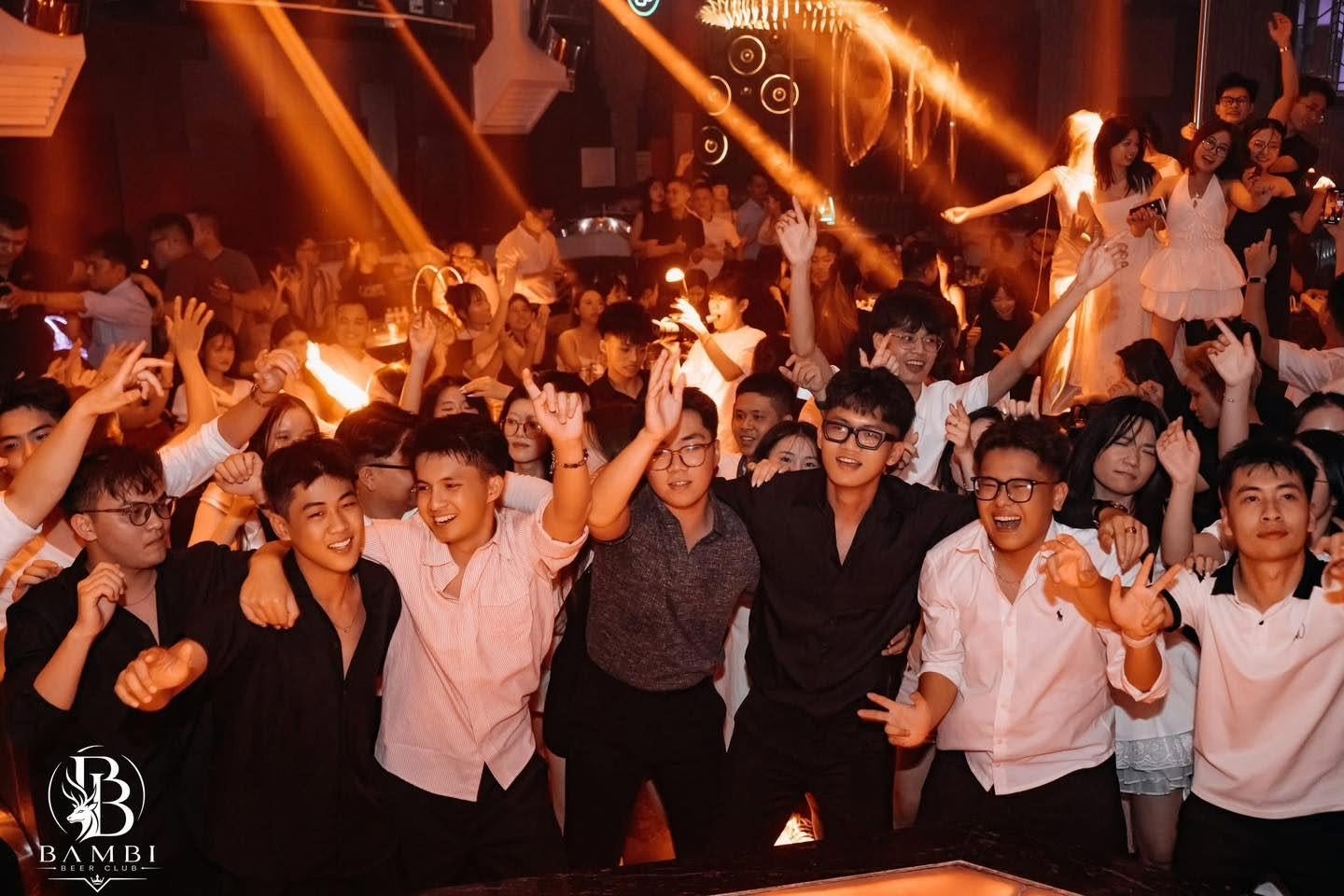 Khách cổ vũ trước sân khấu DJ dưới đèn cam tại Bambi Club